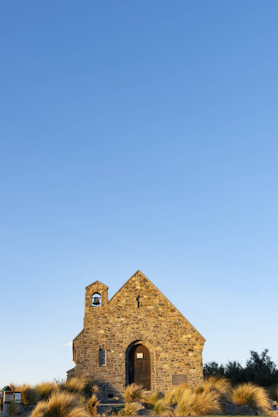 ニュージーランドのカンタベリー州テカポにあるグッドシェパード教会の石の前に太陽が沈む。. - 写真・画像