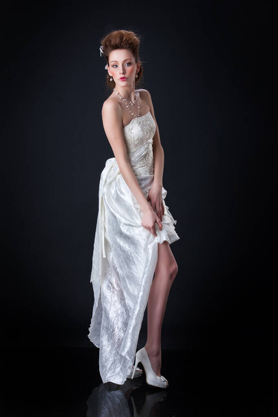 Young woman in wedding dress on a black background - Foto, imagen