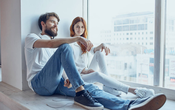 young couple sitting on the windowsill near the window rest fun lifestyle - Foto, Imagen