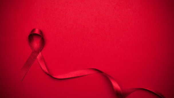 Día del SIDA. Símbolo de cinta roja en el día mundial del VIH sobre fondo rojo oscuro. Ayudas a la concienciación y cáncer. Salud y concepto médico - Foto, imagen