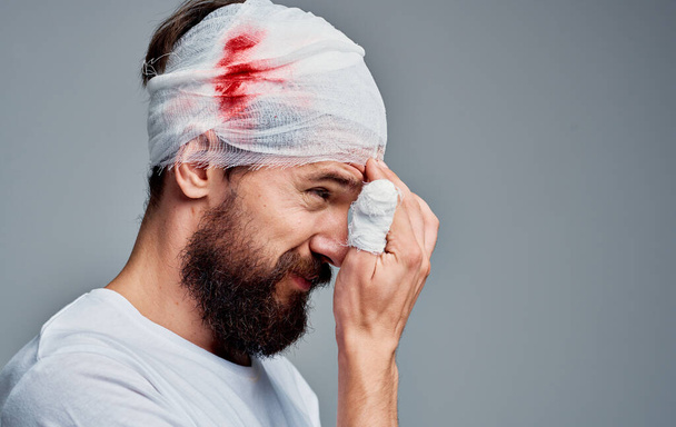 uomo con la testa fasciata e il trattamento del sangue braccio problema ospedaliero lesioni - Foto, immagini