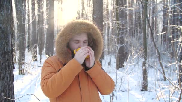 Turismo de invierno y concepto de senderismo. Barba hombre con bebida caliente en el bosque de invierno - Imágenes, Vídeo