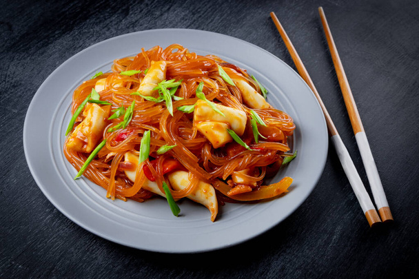  Funchoza with spicy sauce and squid on a plate. Glass noodles, Asian food. High quality photo - Fotografie, Obrázek
