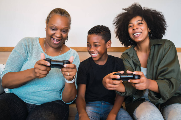 Grandmother, mother and son playing video games at home. - Фото, изображение