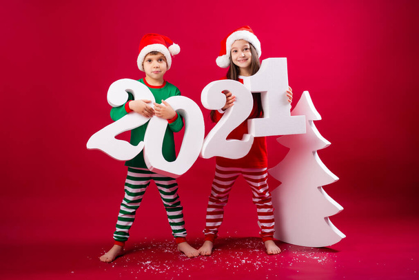 brother and sister in santa hats holding big 2021 numbers - Foto, afbeelding