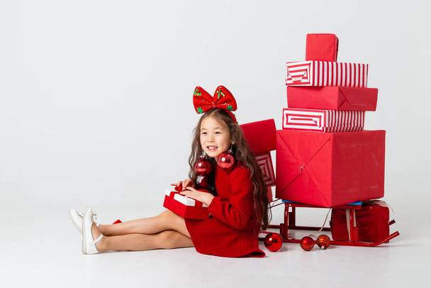 asian girl with bow on head posing with many gifts on white studio background - Foto, imagen