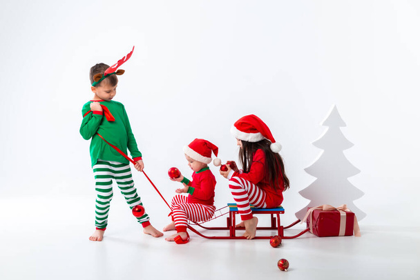 brother carrying boy and girl sitting on sleigh in festive costumes  - Photo, Image
