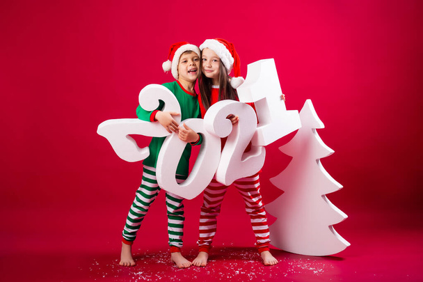 Junge und Mädchen in festlichen Kostümen posieren mit Zahlen von 2021 - Foto, Bild