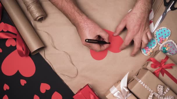 , Męskie dłonie piszą wyrażenie "kocham cię" na papierowym sercu. Koncepcja świętowania Valentine. - Materiał filmowy, wideo