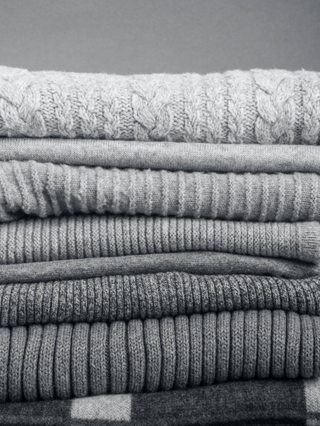 究極のグレーを基調としたニットファッショナブルなグレーウールのテクスチャの布のクローズアップ、暖かいセーターの山、スカーフ。流行カラー2021のデモンストレーション - 写真・画像