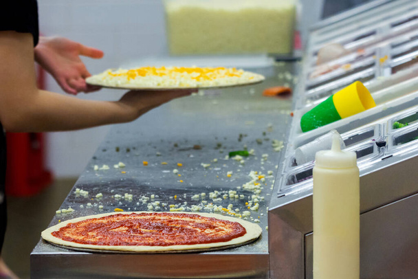 Aşçı mutfakta, pizzanın malzemelerini koyuyor. Pizza konsepti. Gıda üretimi ve teslimatı. - Fotoğraf, Görsel