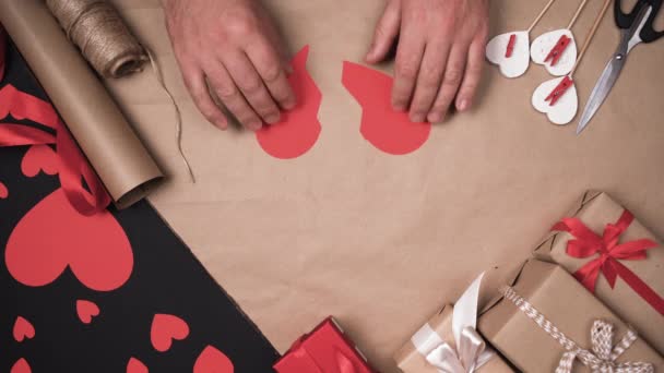 Männer Hände versuchen, das in Stücke geschnittene Papierherz zu verbinden. Das Konzept, Beziehungen nach der Scheidung zu entscheiden. - Filmmaterial, Video