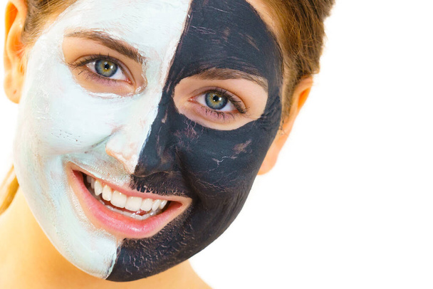Woman with clay carbo black mask on half face and white mud on second half. Girl taking care of oily complexion. Beauty procedures. Skincare. - Foto, Bild