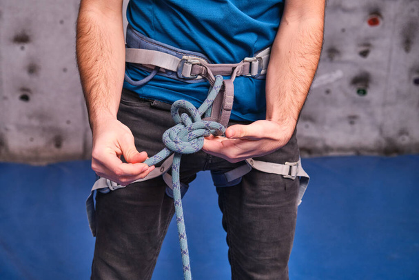 Close-up of climber with climbing equipment, tying knot on safety climbing harness, preparing for climbing. Unrecognizable person detail. - Foto, Bild
