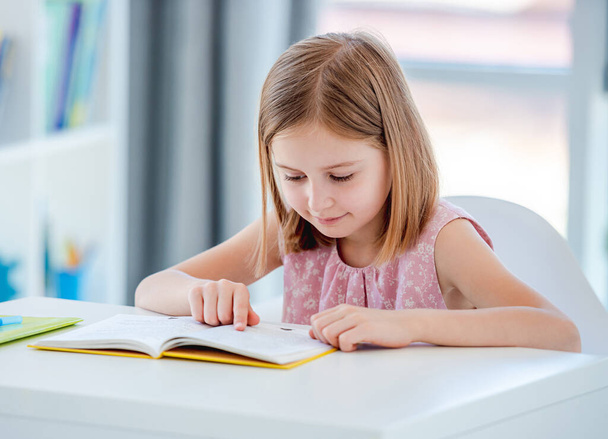 Little girl reading book in classroom - Fotoğraf, Görsel