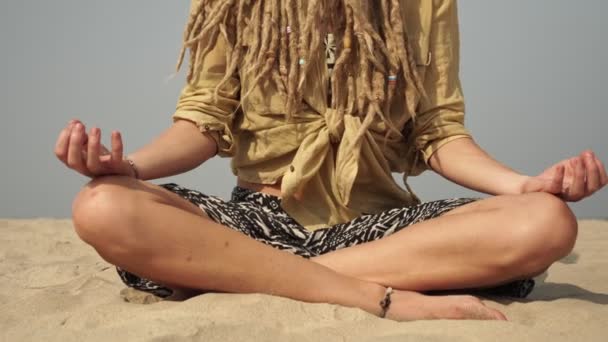 Hipisowska kobieta praktykuje jogę i medytację w pozycji lotosu nad morzem - Materiał filmowy, wideo
