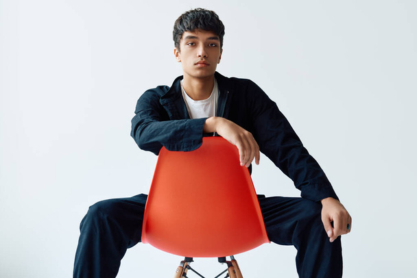 Stylish handsome young man posing on studio sitting on a chair looking to camera - Photo, Image