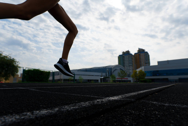 Een atleet die hardloopt op een atletiekbaan en haar cardio traint. Vrouw joggen voor wedstrijd race in de zomer outdoor stadion. - Foto, afbeelding