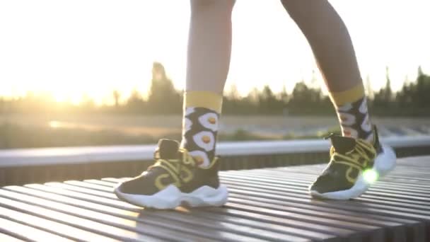 Mujer joven en zapatillas deportivas camina por la calle - Metraje, vídeo