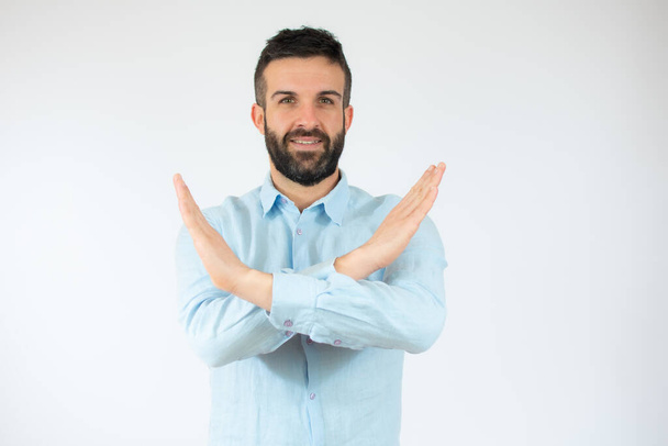 Jeune homme portant une chemise décontractée sur fond blanc Expression de rejet croisement des bras et des paumes faisant signe négatif. - Photo, image
