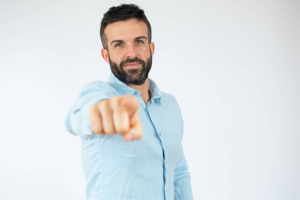 Young man wearing casual blue shirt pointing finger to camera over white background. - Foto, imagen
