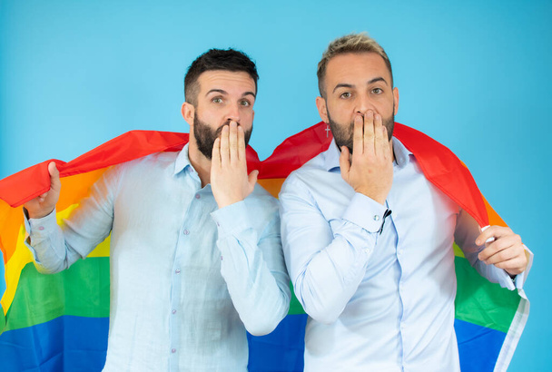 Молода гей-пара тримає прапор над синім тлом
. - Фото, зображення