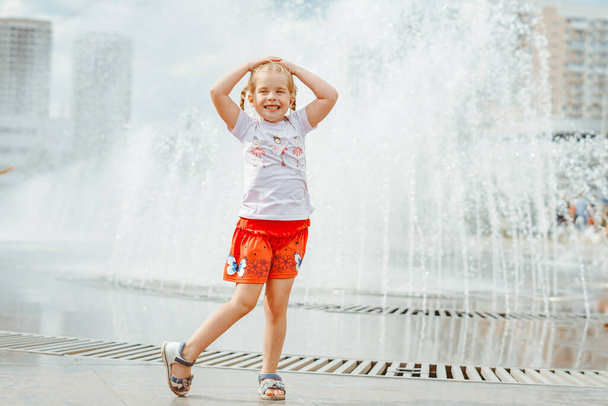 bambina vicino alla fontana in gonna rossa con le trecce - Foto, immagini
