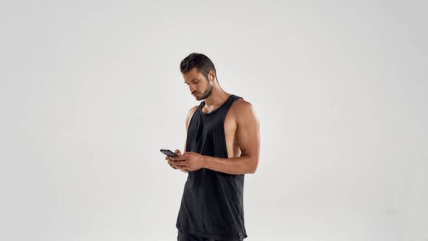 Young handsome caucasian athlete holding smartphone - Фото, изображение