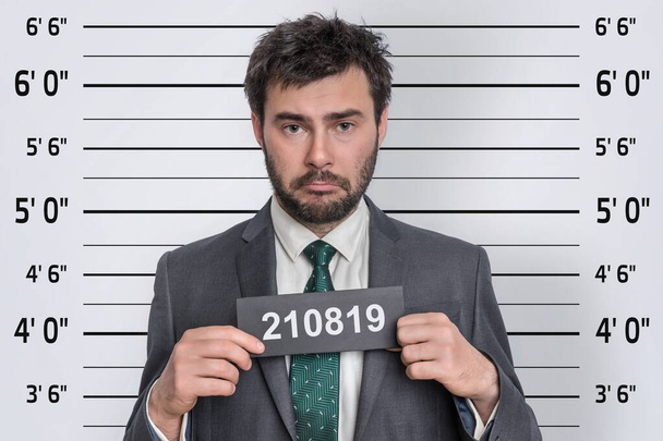 Poliisiasemalla puvussa olevan miehen pidätyskuva - vangin tunnistamisen käsite - Valokuva, kuva