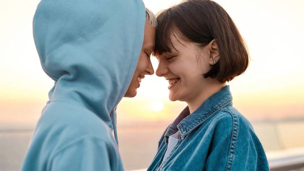 Close up of young loving lesbian couple smiling while going to kiss, Two women enjoying romantic moments together at sunrise - Foto, imagen