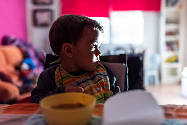 Νεαρό παιδί βλέπει τηλεόραση ενώ τρώει - Φωτογραφία, εικόνα