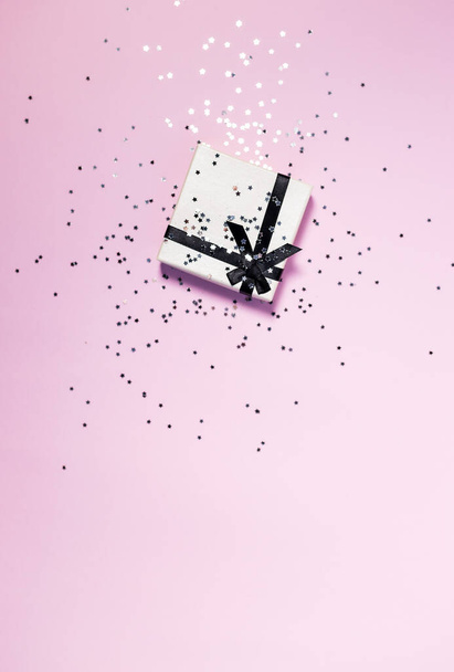 Gift or present box and stars confetti on pink table top view. Flat lay composition for birthday,valentines Day,mother day or wedding. - Foto, imagen