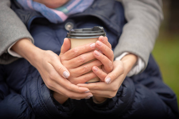 Κοντινά γυναικεία χέρια με ένα φλιτζάνι καφέ. Φθινοπωρινή βόλτα. - Φωτογραφία, εικόνα