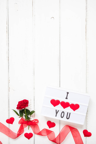 Valentine's day, love, romantic concept. Fresh red rose flower with ribbon and text I love you on lightbox on white wooden background. Greeting card. Flat lay, top view, copy space. - Φωτογραφία, εικόνα