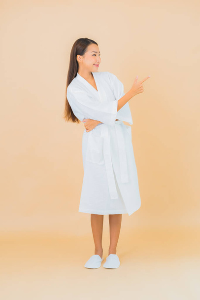 Retrato bonito jovem asiático mulher desgaste roupão de banho com sorriso na cor de fundo - Foto, Imagem
