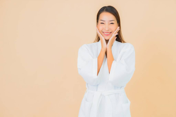 Retrato bonito jovem asiático mulher desgaste roupão de banho com sorriso na cor de fundo - Foto, Imagem