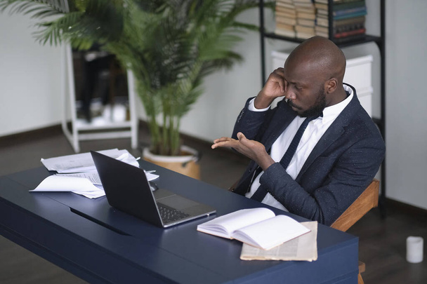 Poważny Afroamerykanin prowadzi trudne negocjacje telefoniczne. Head shot zamyślony młody Afrykanin amerykański pracownik międzynarodowej firmy menedżer pracy z ciężkim zadaniem w miejscu pracy. - Zdjęcie, obraz