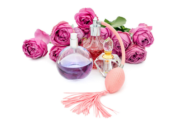 Parfumflesjes met bloemen op witte achtergrond. Parfumerie, cosmetica, geurcollectie. - Foto, afbeelding
