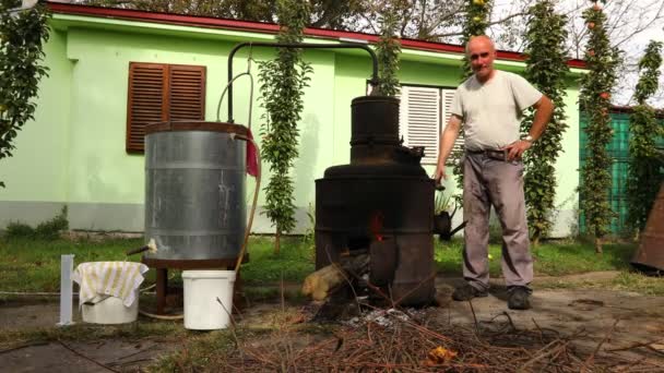 Man is manually turning lever to mix fruit marc in boiler of homemade distillery made of copper, making moonshine schnapps, alcoholic beverages such as brandy, cognac, whiskey, bourbon, gin, scotch. - Footage, Video