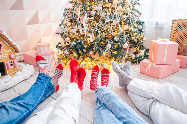 Close up photo of family feet in woolen socks by the christmas tree - Фото, изображение