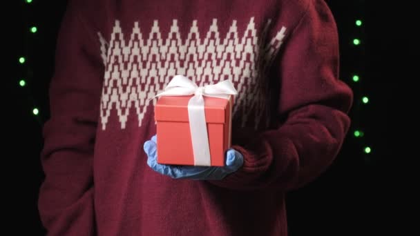 маленькие дети рука в синих защитных перчатках давая подарочную коробку с белой лентой - Кадры, видео