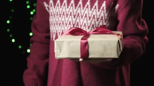 primer plano en la caja de mano de los niños con cinta roja. navidad, concepto de año nuevo - Imágenes, Vídeo
