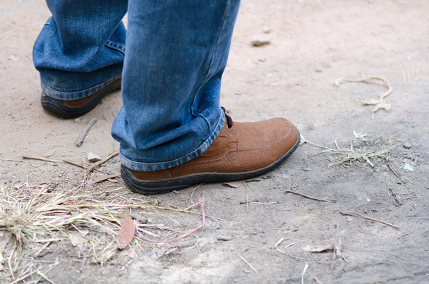 Piede umano con scarpe e jeans in pelle marrone
 - Foto, immagini