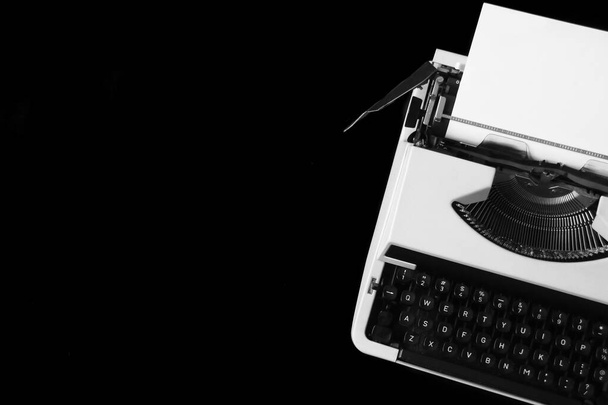 vista dall'alto primo piano piatto lay foto di vecchia macchina da scrivere con carta bianca in esso su sfondo nero con spazio di copia - Foto, immagini