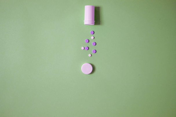 modern minimalist photo of open bottle, purple and white tablets on bright green background with copy space - Valokuva, kuva