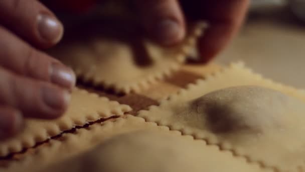 Primo piano delle donne mano che separano i ravioli l'uno dall'altro dopo essere stati tagliati. Preparare i ravioli, un piatto tipico italiano, fatto in casa secondo l'antica tradizione italiana. Video 4K. - Filmati, video
