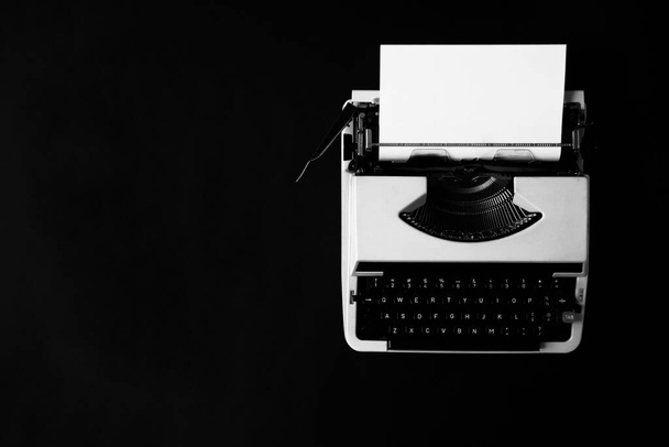 płaski leżał zdjęcie starej maszyny do pisania z białym pustym papierem w nim na czarnym tle z miejsca kopiowania - Zdjęcie, obraz