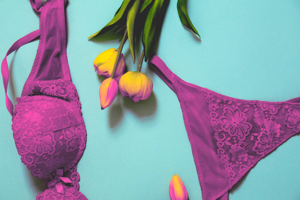 photo minimaliste colorée rétro de femmes sexy dentelle sous-vêtements et tulipes sur fond bleu vif - Photo, image