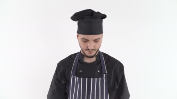 Serieuze chef-kok in uniform loopt dicht op zoek naar camera, over witte achtergrond - Video