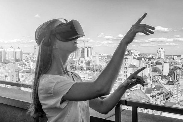 仮想現実ゴーグルヘッドセット、 VRボックスを屋外で身に着けている若い女性。接続、技術、新世代、進歩の概念。仮想現実で物に触れようとする少女. - 写真・画像